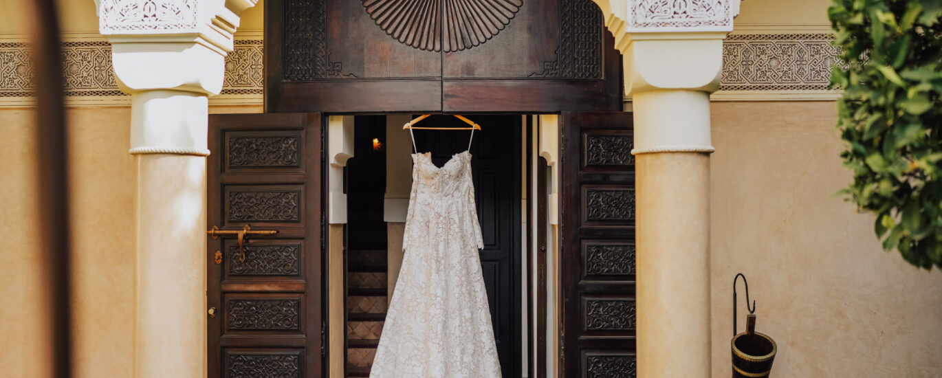 Vue d'ensemble d'une réception de mariage de luxe dans un riad marocain, patio éclairé à la bougie, table dressée avec vaisselle dorée