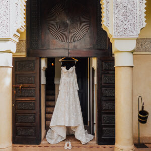 Vue d'ensemble d'une réception de mariage de luxe dans un riad marocain, patio éclairé à la bougie, table dressée avec vaisselle dorée