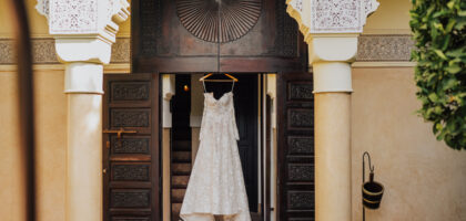Vue d'ensemble d'une réception de mariage de luxe dans un riad marocain, patio éclairé à la bougie, table dressée avec vaisselle dorée