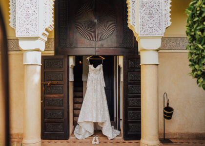 Vue d'ensemble d'une réception de mariage de luxe dans un riad marocain, patio éclairé à la bougie, table dressée avec vaisselle dorée