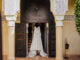 Vue d'ensemble d'une réception de mariage de luxe dans un riad marocain, patio éclairé à la bougie, table dressée avec vaisselle dorée